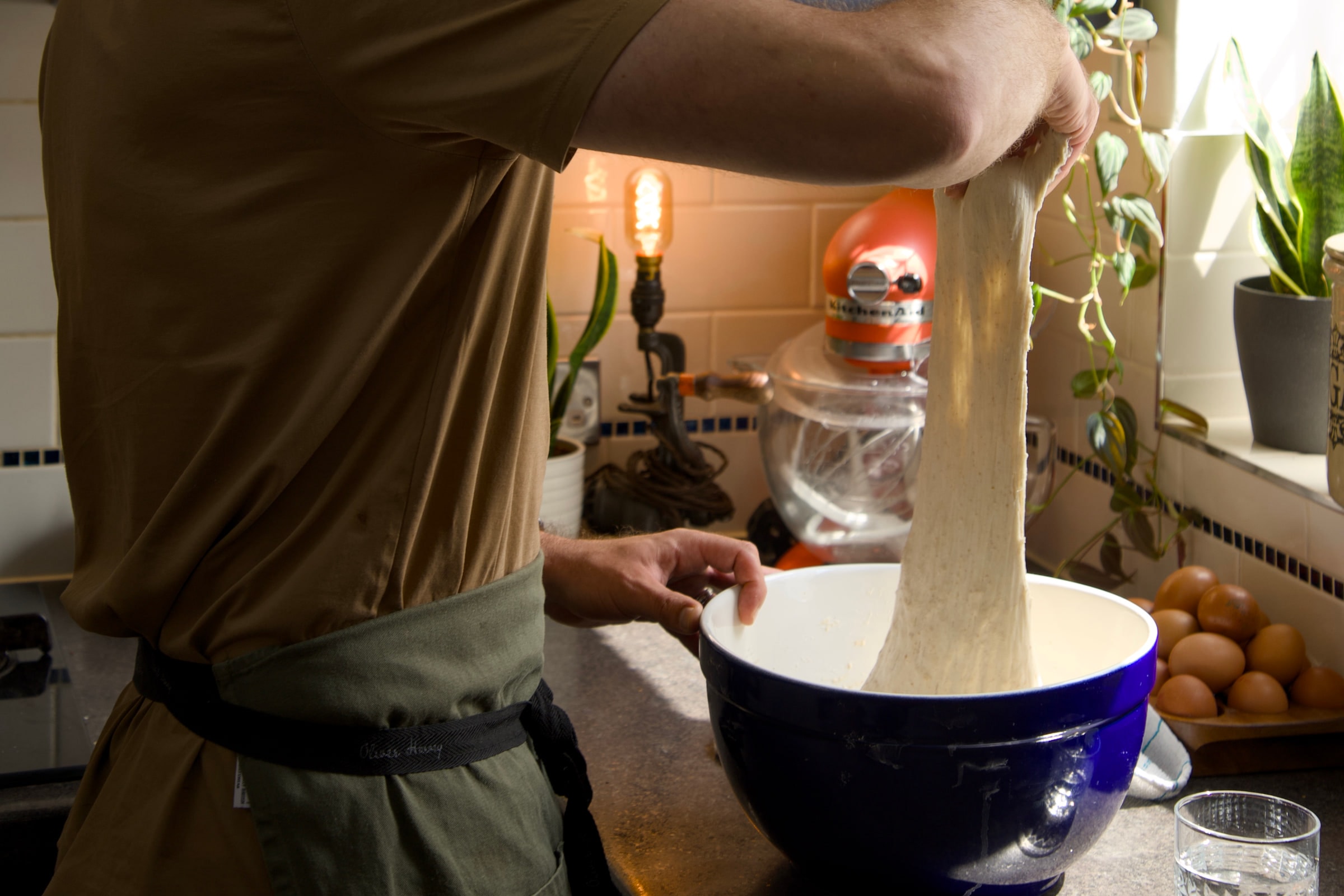 Tom tipping flour into a blue mixing bowl beside a stand mixer