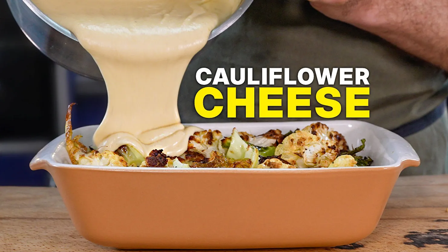 Cheese sauce is poured over roasted cauliflower in a brown dish. Bold yellow text reads "Cauliflower Cheese."