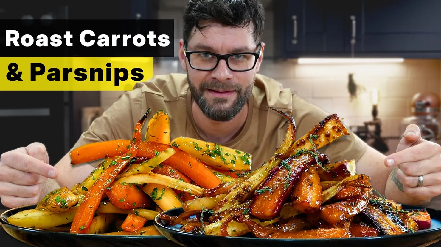 Man smiling in a kitchen with plates of glazed roast carrots and parsnips. Text reads: "Roast Carrots & Parsnips" in bold black and yellow.