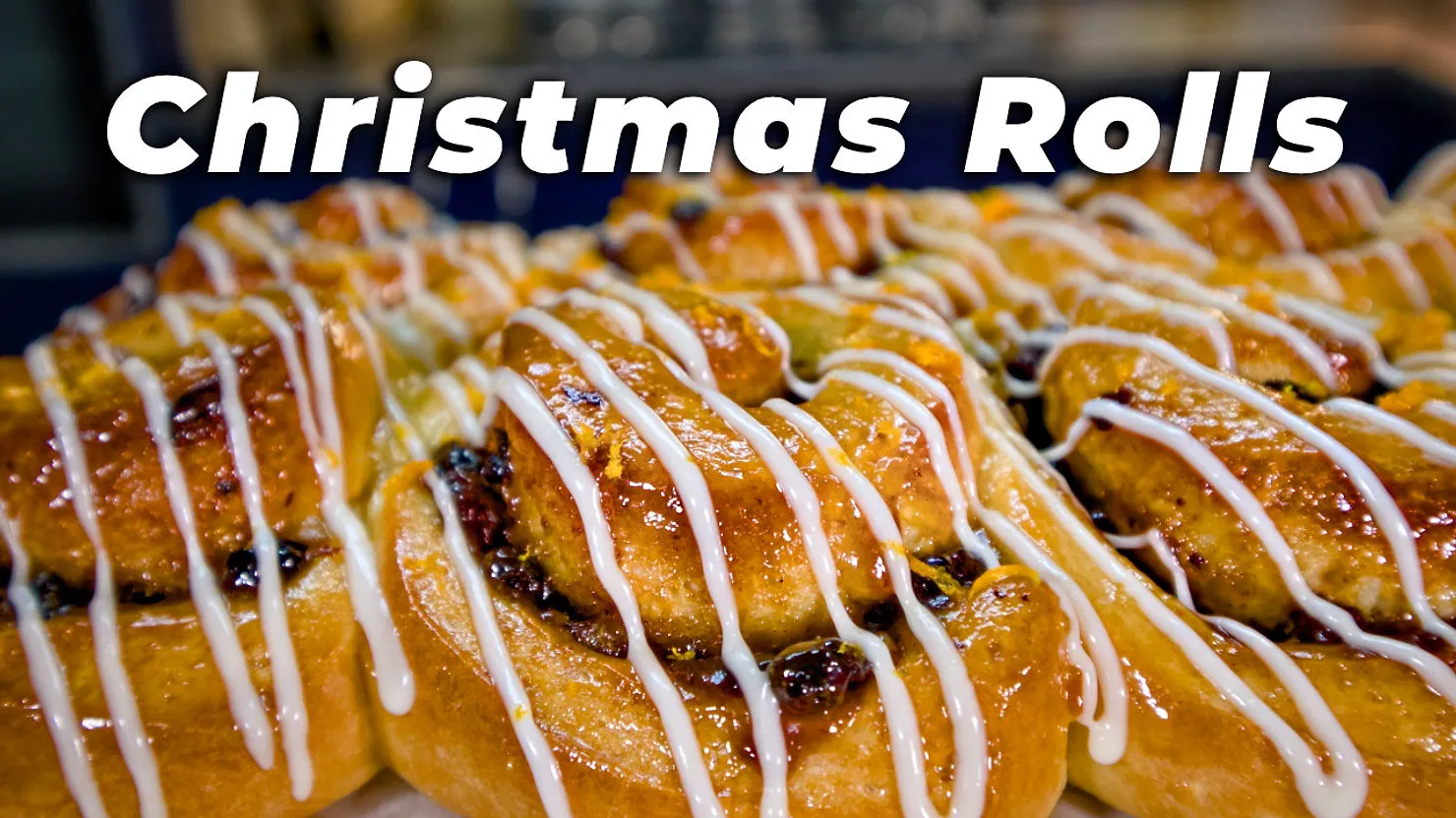 Close-up of glazed Christmas rolls drizzled with icing. Text reads "Christmas Rolls" in bold above the warm, golden pastries.