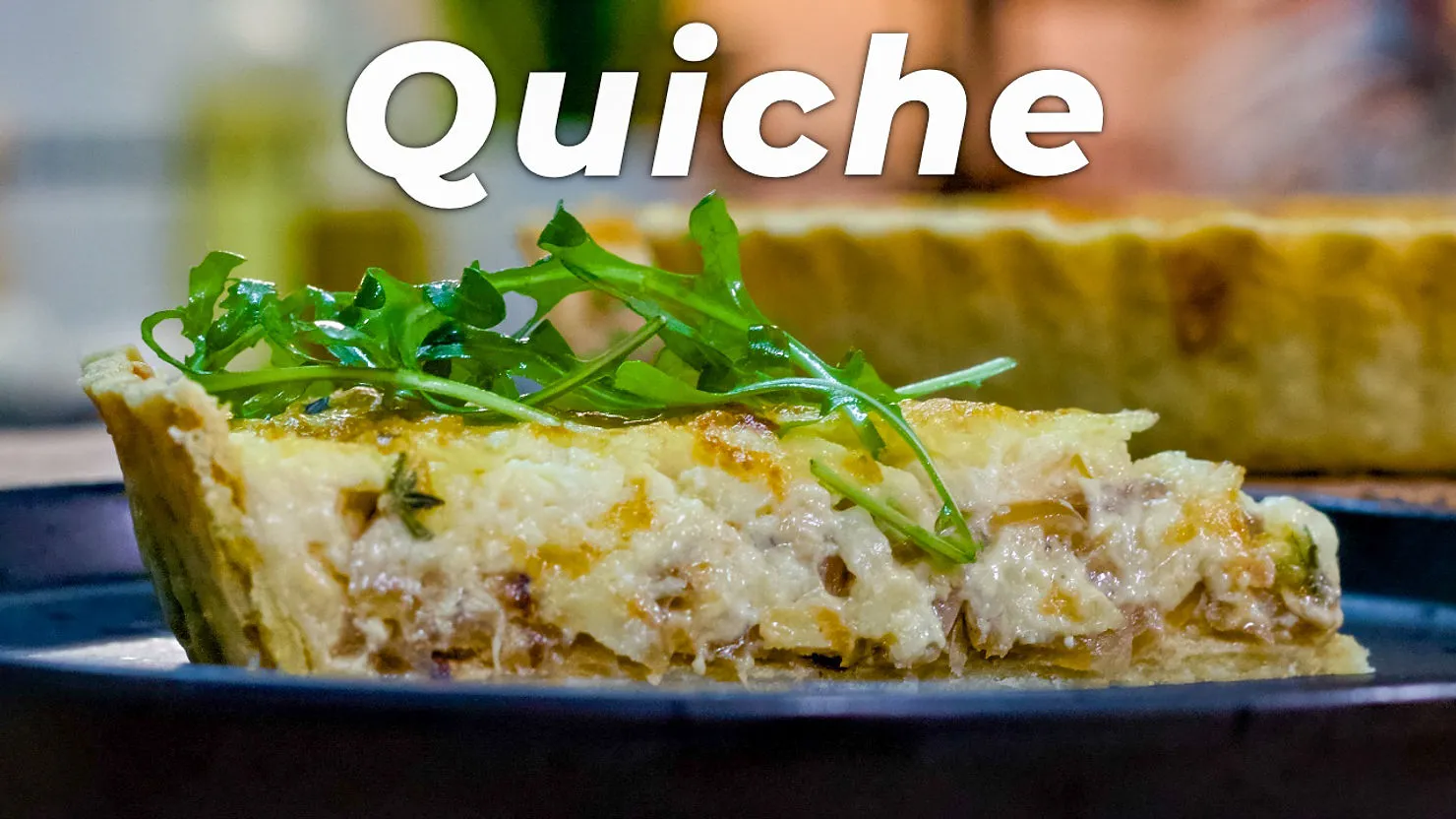 A slice of quiche topped with fresh arugula on a dark plate. The word "Quiche" is displayed in bold text above, creating a bright, appetizing mood.