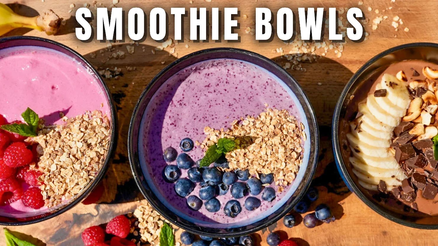 Three smoothie bowls on a wooden table: pink with raspberries, purple with blueberries, brown with banana slices. Text reads "SMOOTHIE BOWLS".